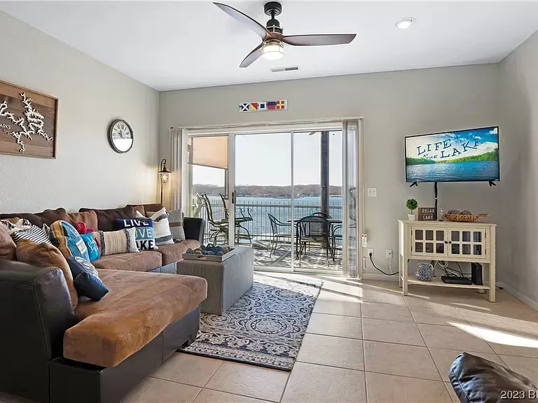 A living room with a couch , television , and ceiling fan.