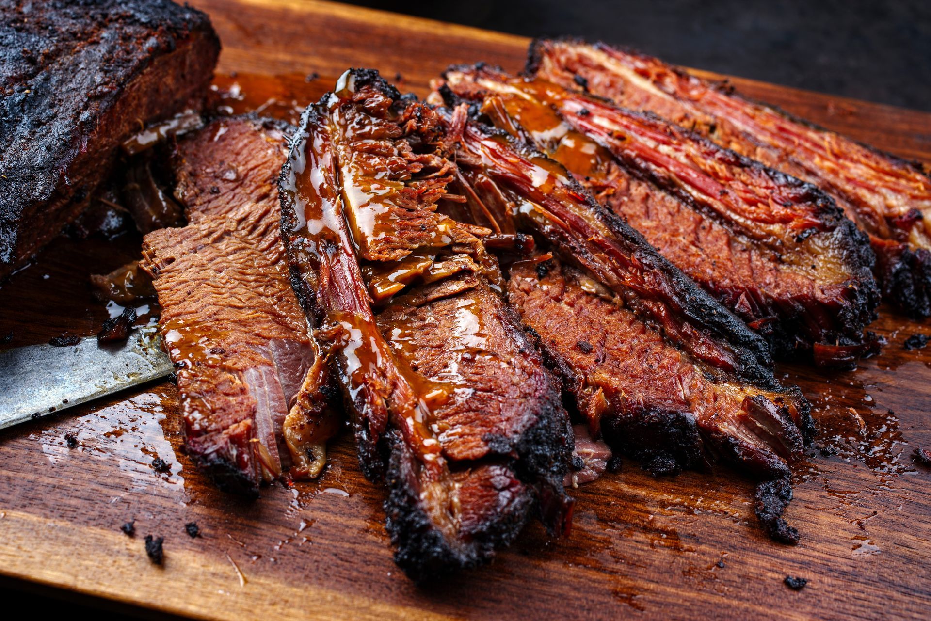 A close up of a sliced brisket on a wooden cutting board.