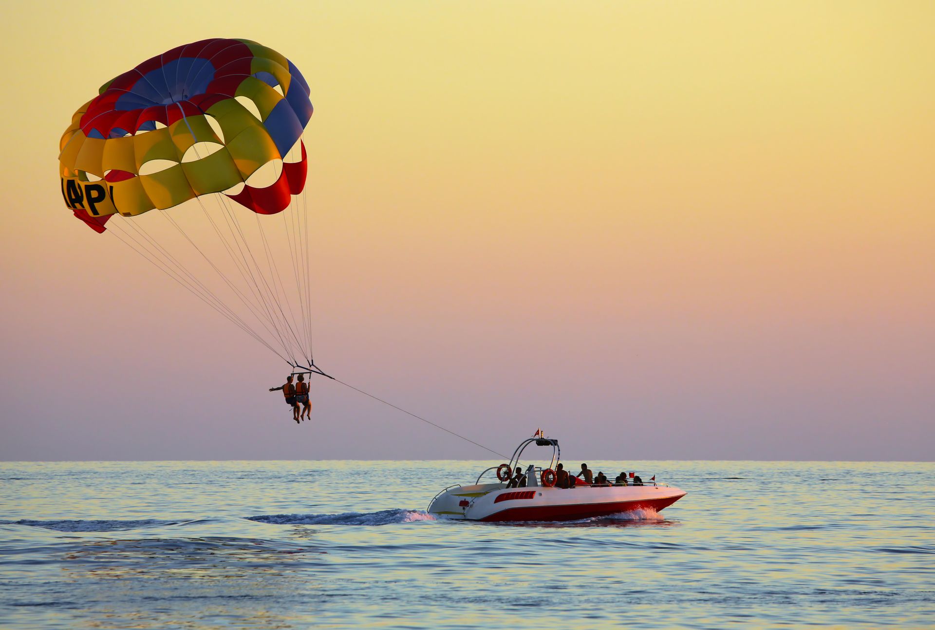 A person is parasailing over the ocean next to a boat.