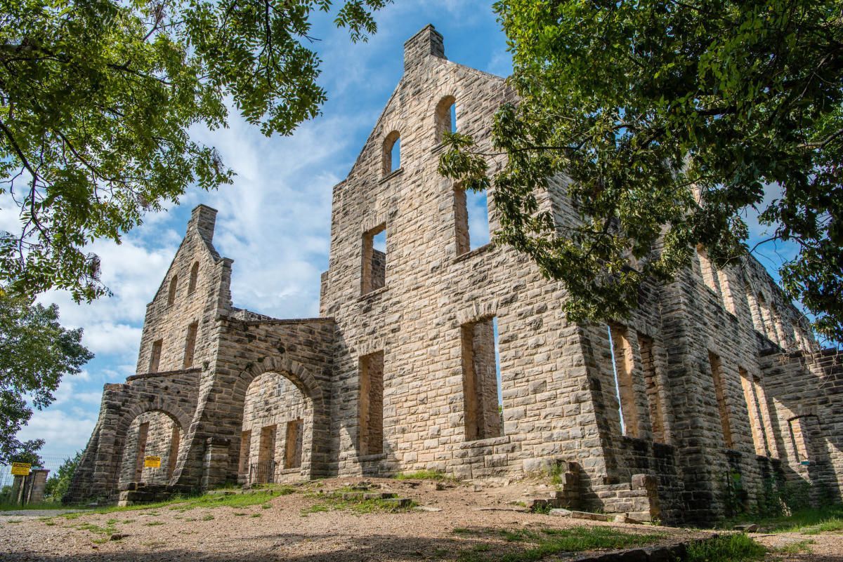 A large stone building is sitting on top of a hill surrounded by trees.