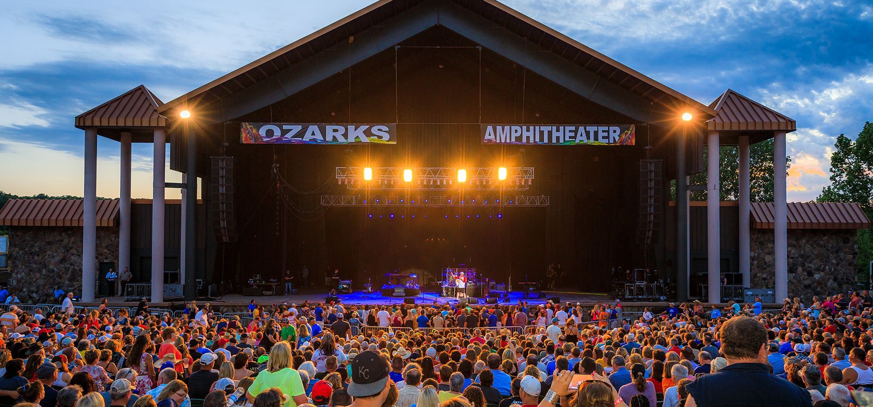 A large crowd of people are sitting in front of a stage at a concert.