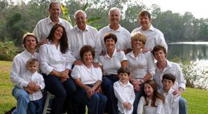 A large family is posing for a picture in front of a lake.