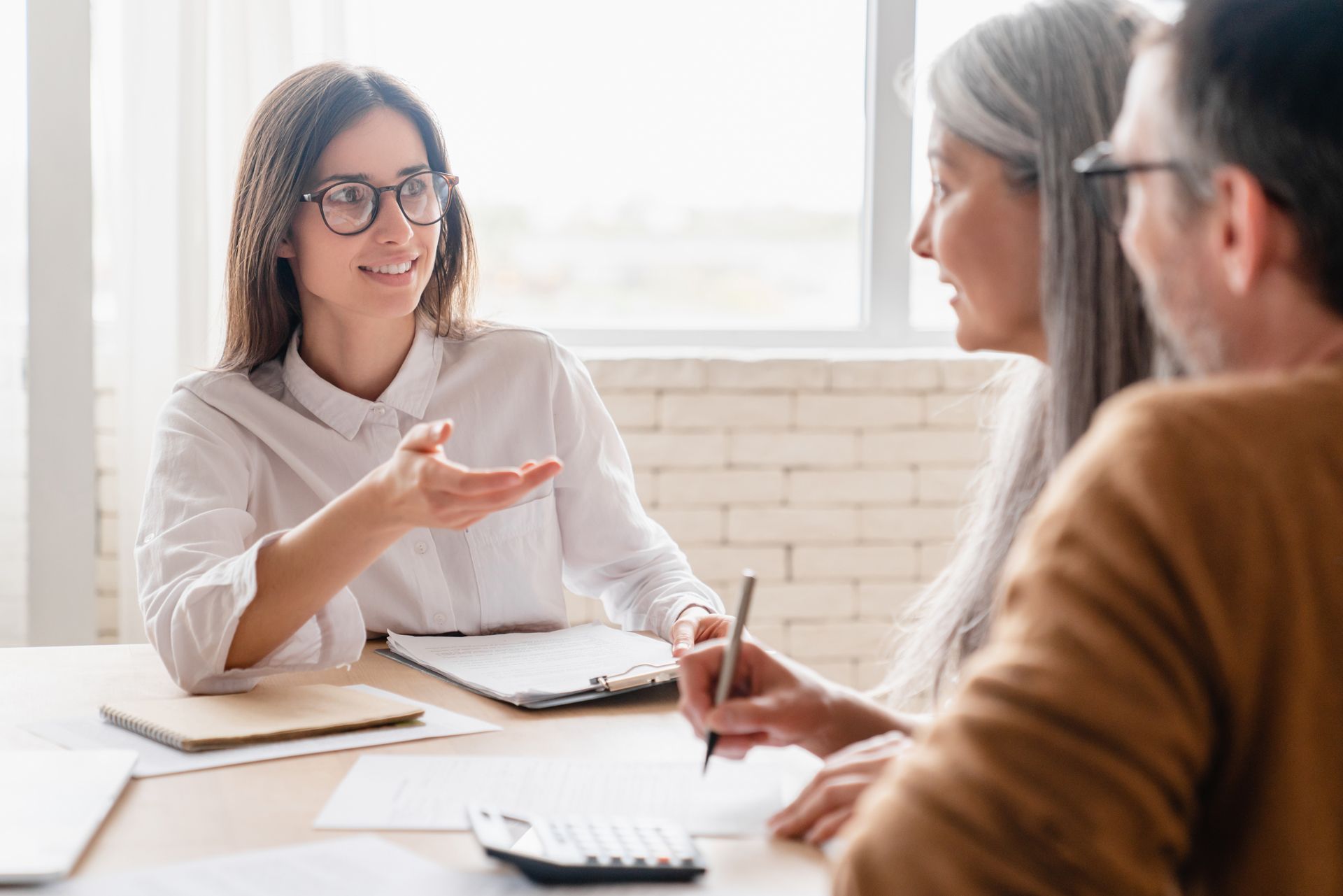 A woman is sitting at a table talking to a man and woman