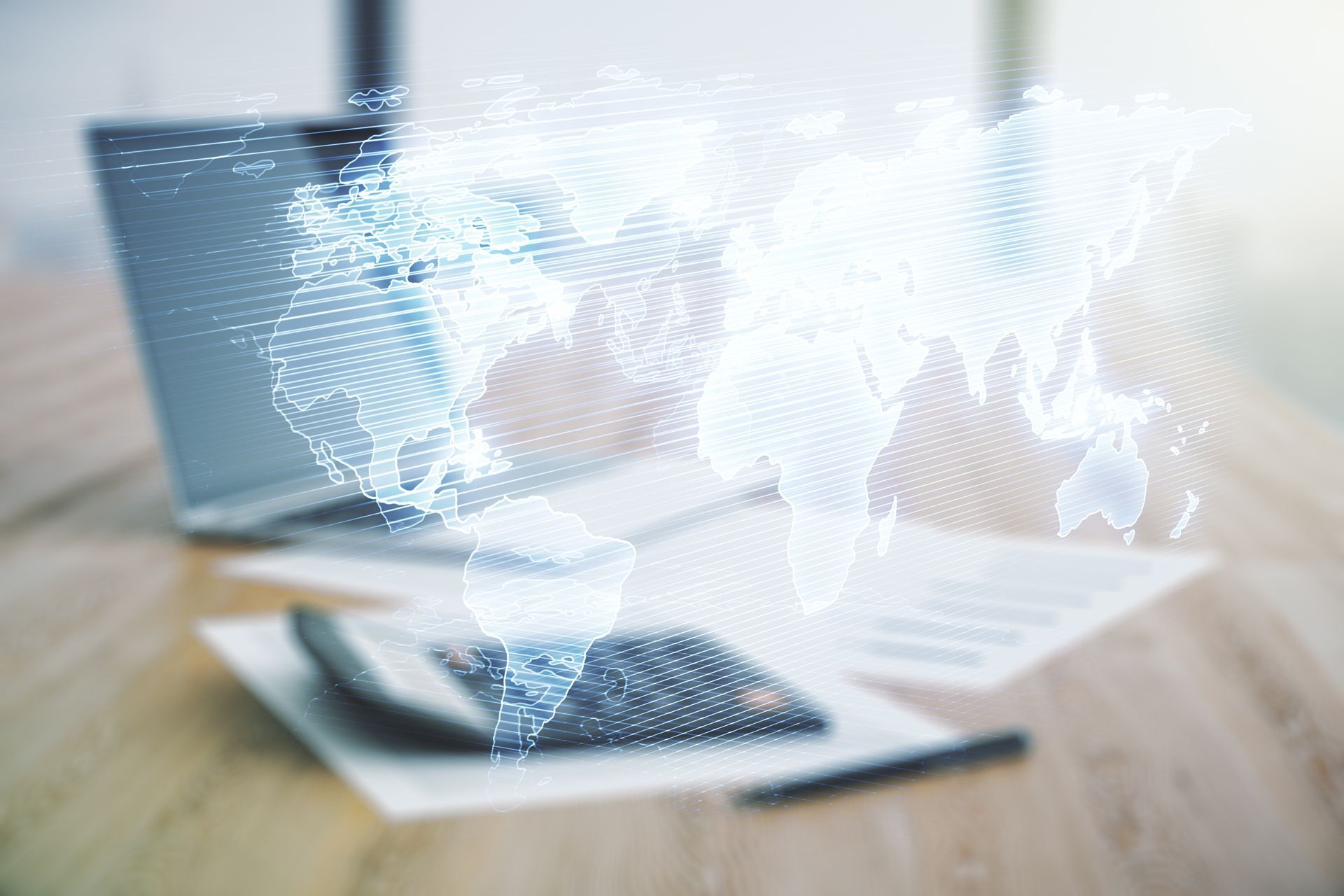 A laptop computer is sitting on a wooden table with a map of the world coming out of it.