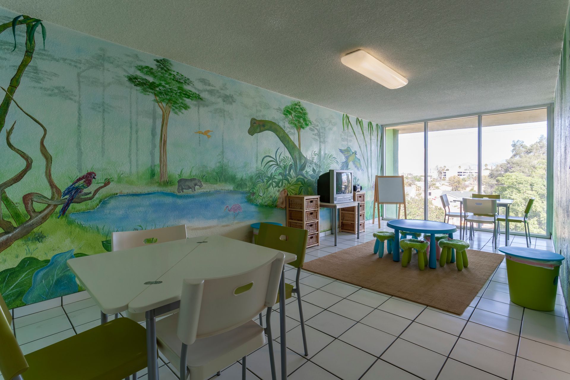 A room with tables and chairs and a mural on the wall