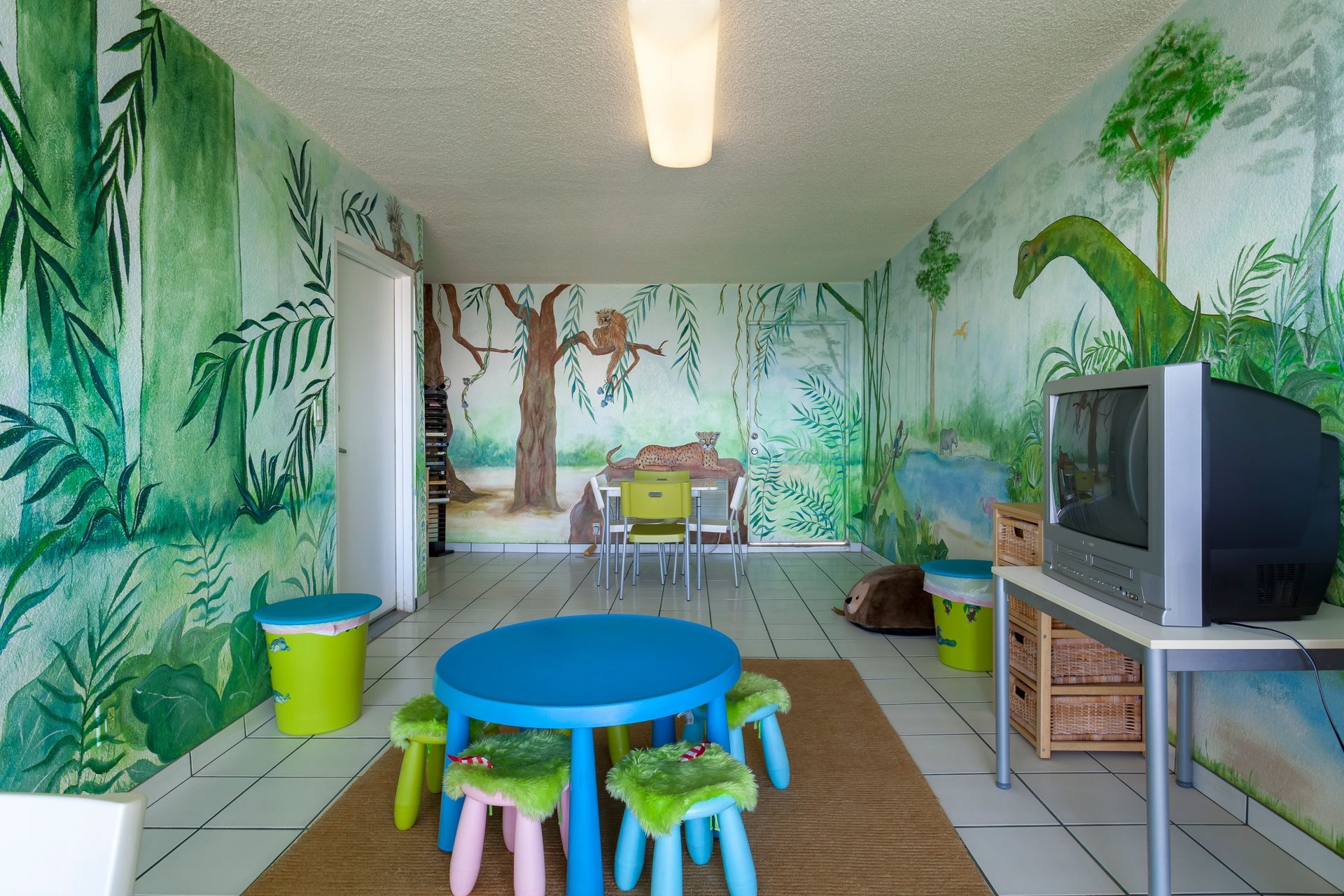A children 's room with a table and chairs and a television.