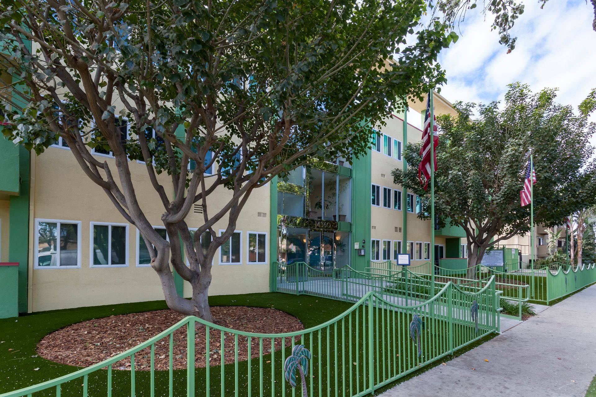 A building with a green fence and a tree in front of it