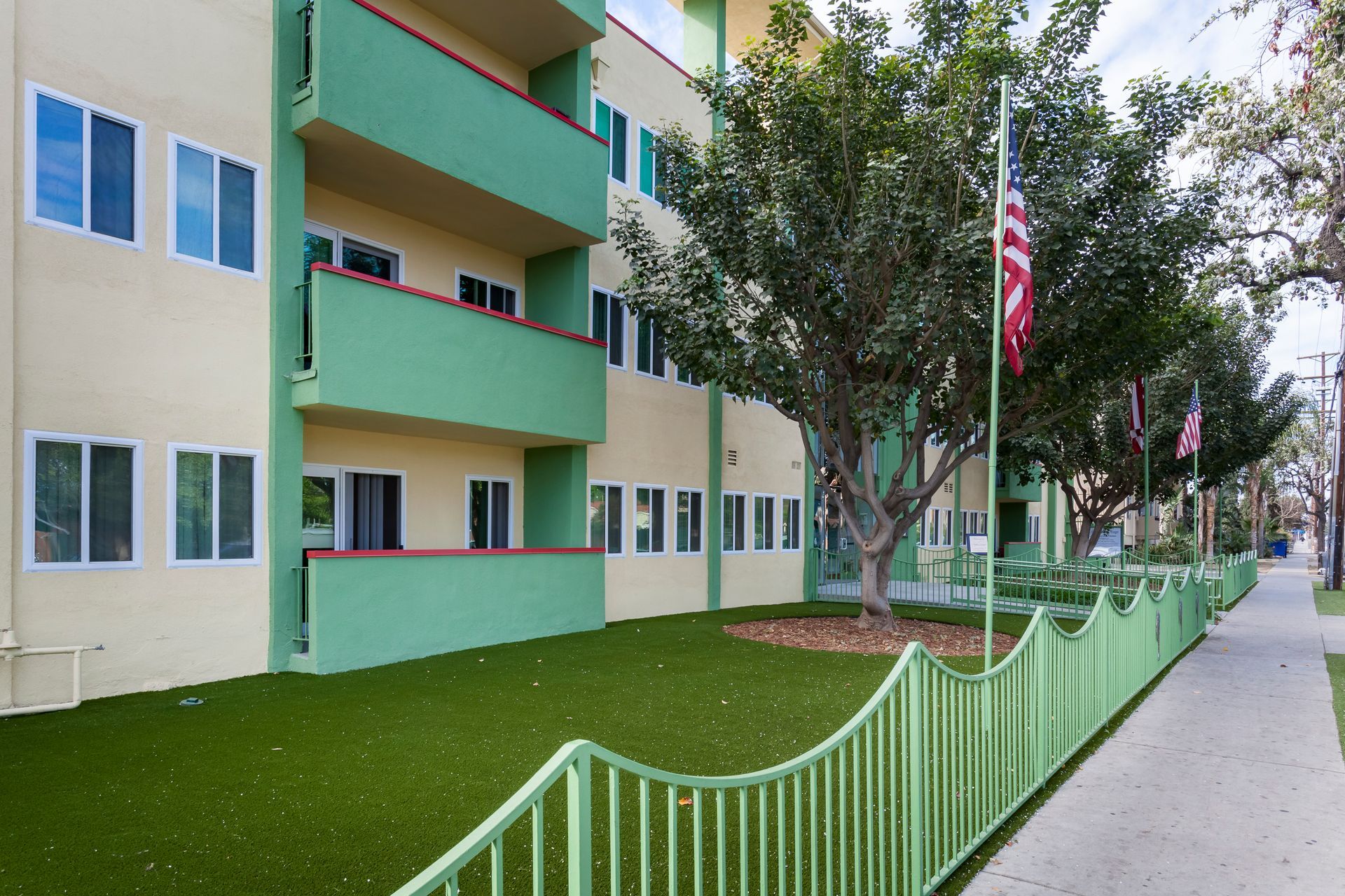 A building with a green fence and a tree in front of it