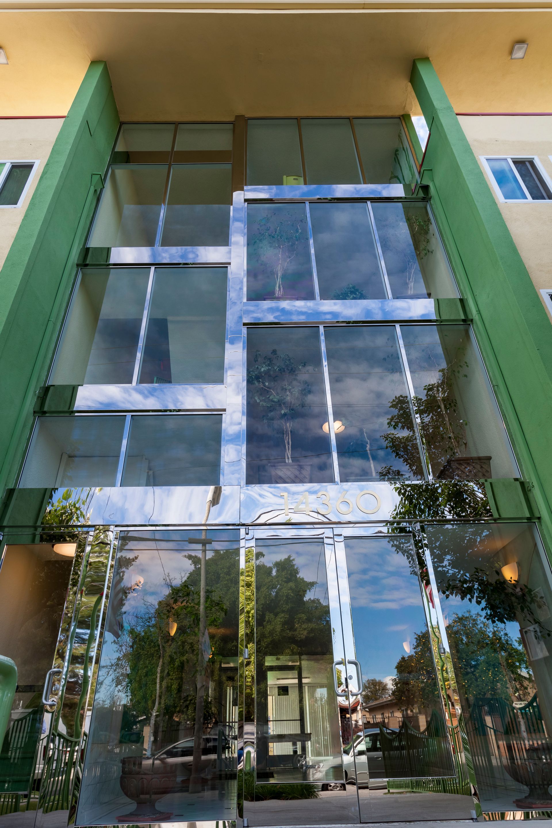 A building with a lot of windows and trees reflected in the windows