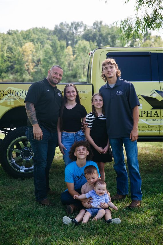 A family is posing for a picture in front of a truck.