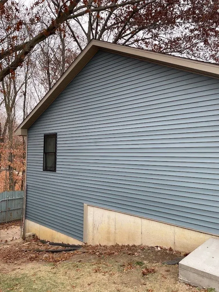 The side of a house with a blue siding and a window.