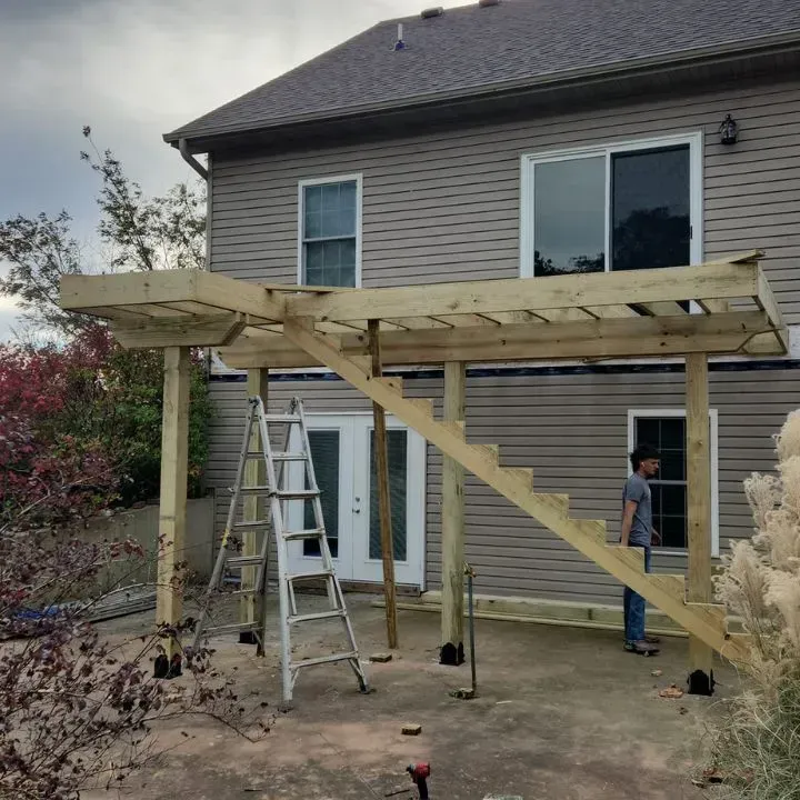 A wooden deck is being built in front of a house