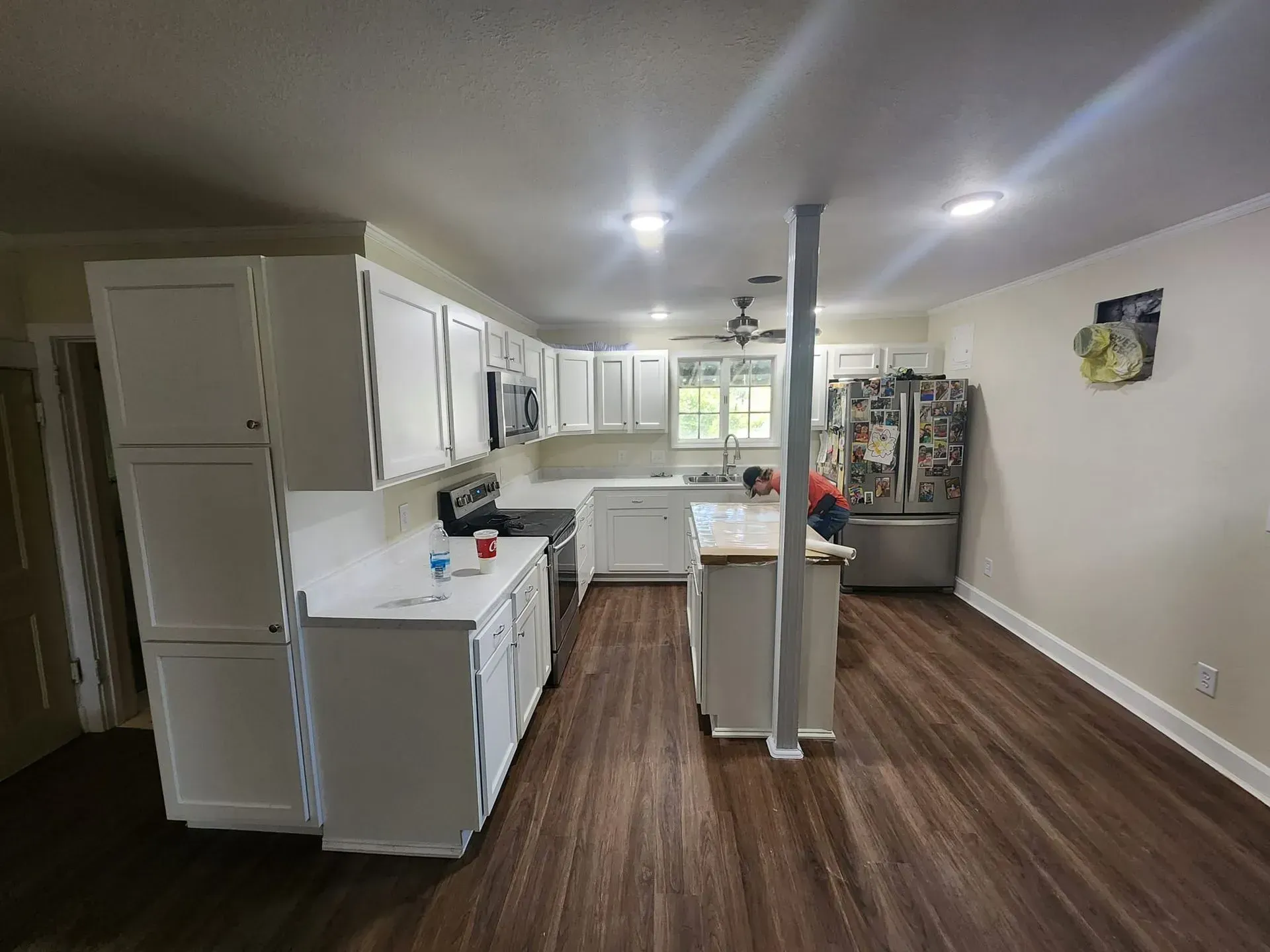 A kitchen with white cabinets , stainless steel appliances , and hardwood floors.
