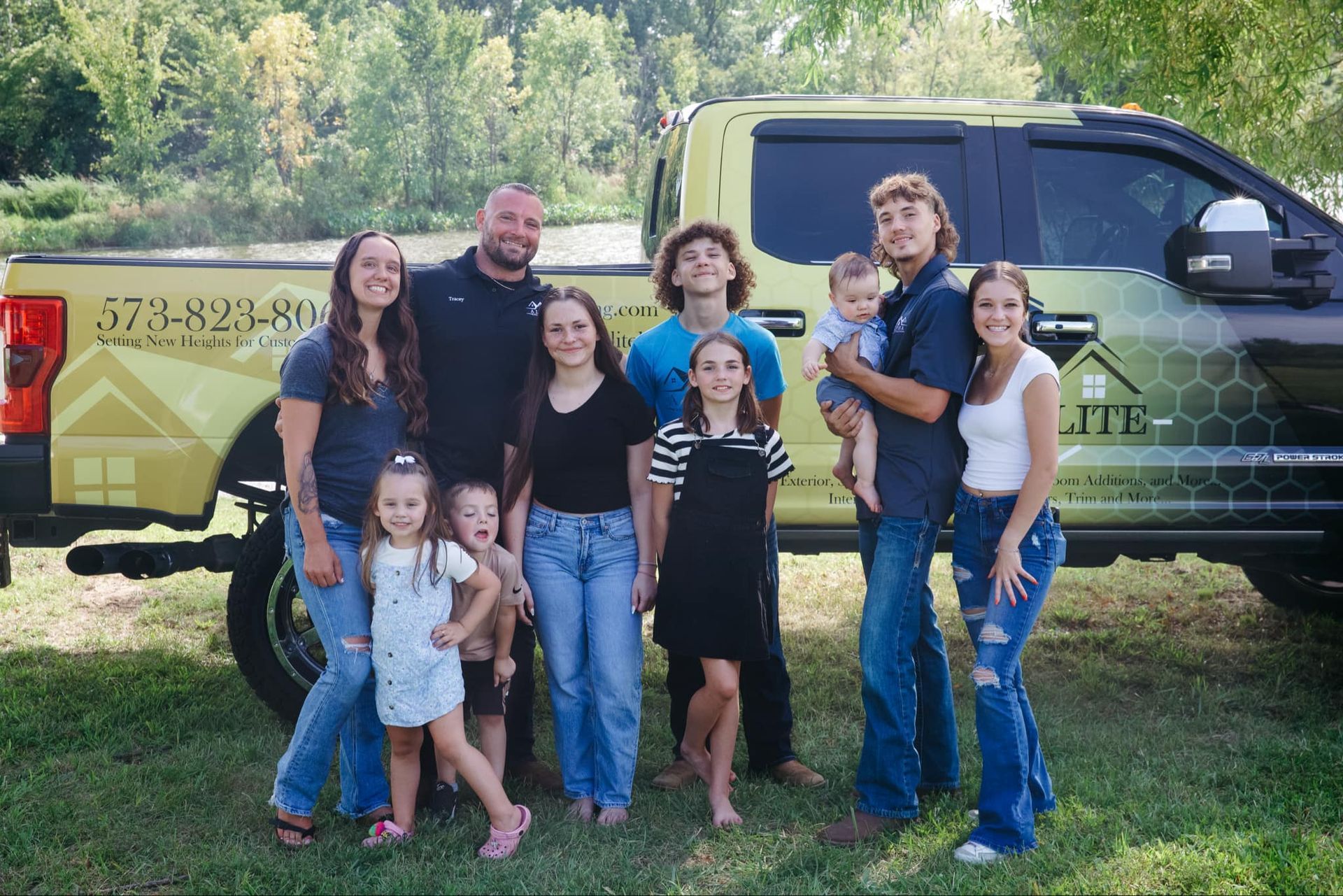 A large family is posing for a picture in front of a truck.