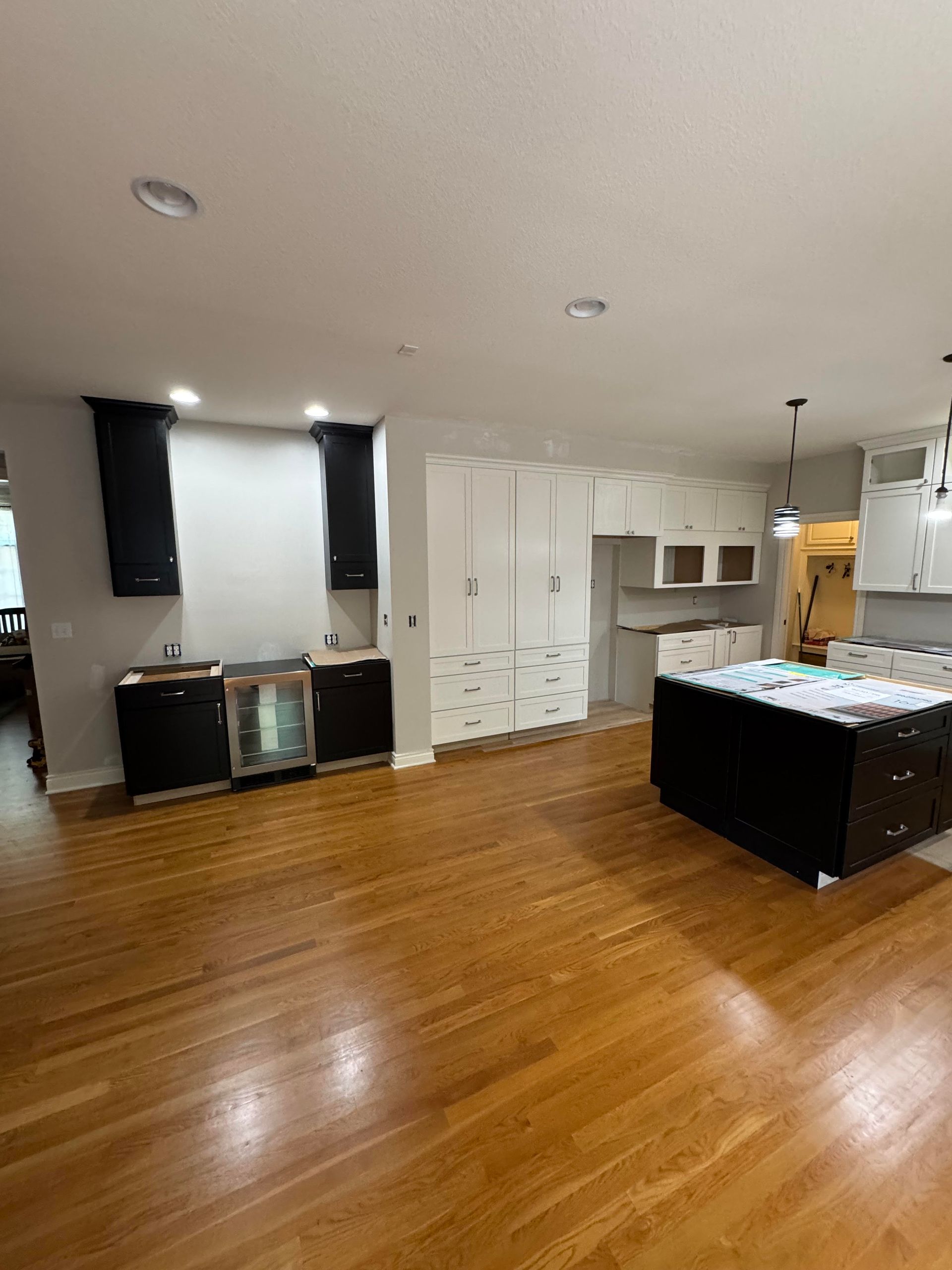 Kitchen under construction with hardwood floors, white cabinets, and dark island.