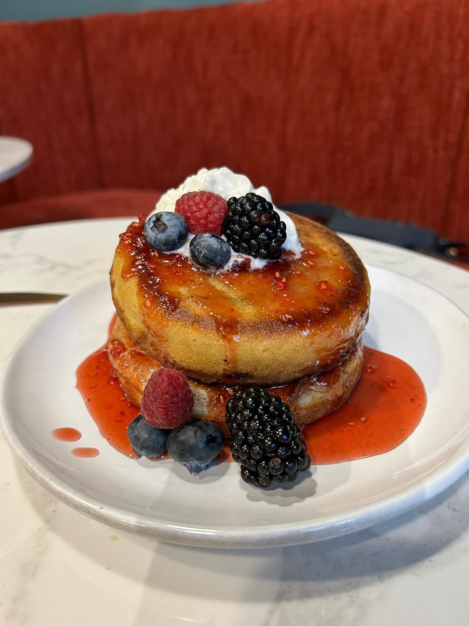 A stack of pancakes with berries on top on a white plate