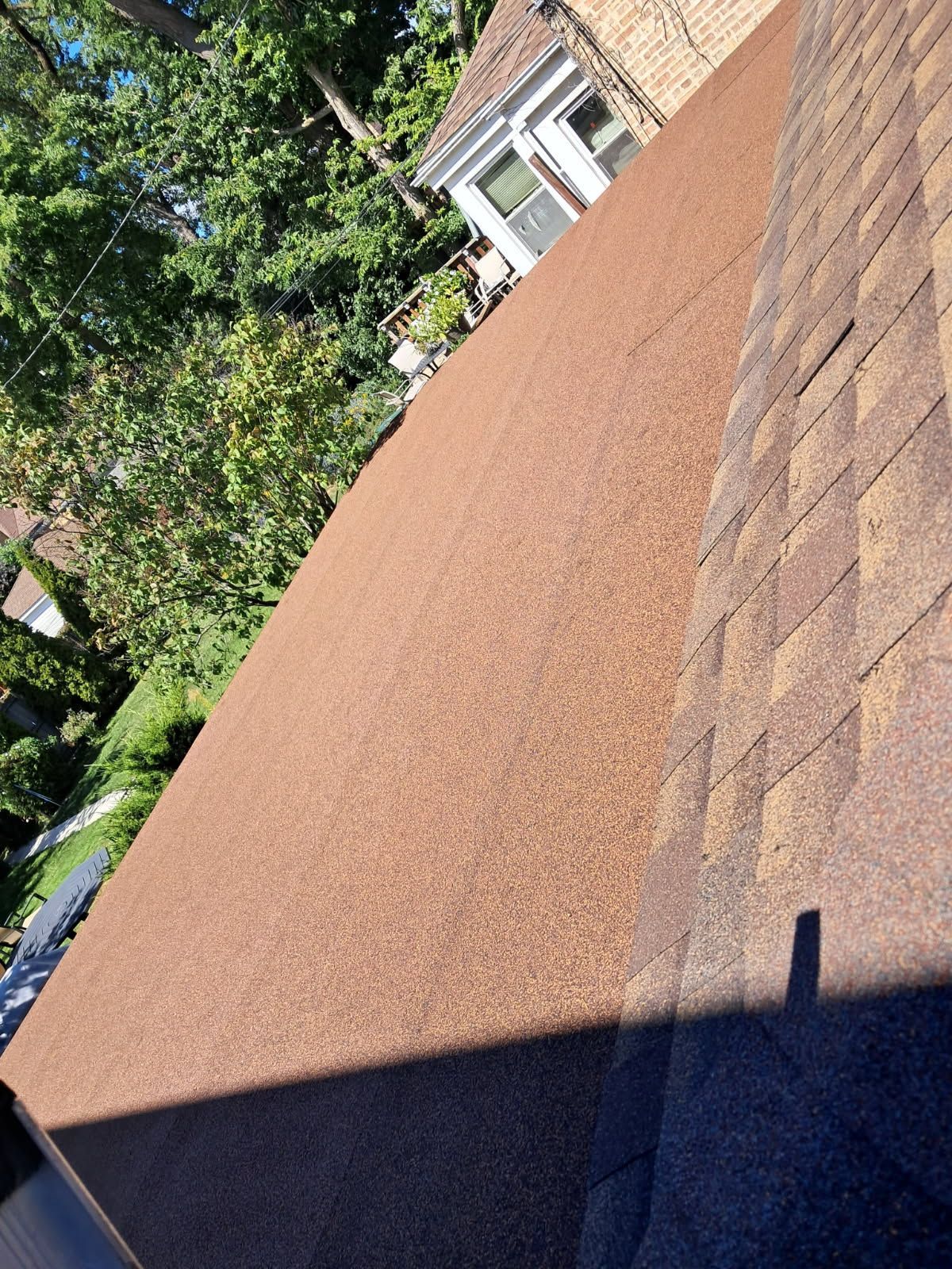 A close up of a brown roof with a house in the background.