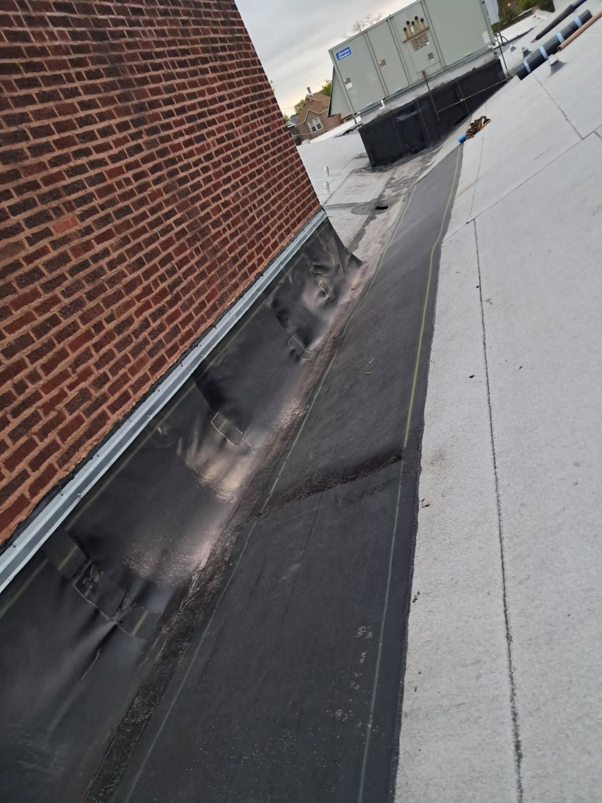The roof of a building with a brick wall and a white roof.