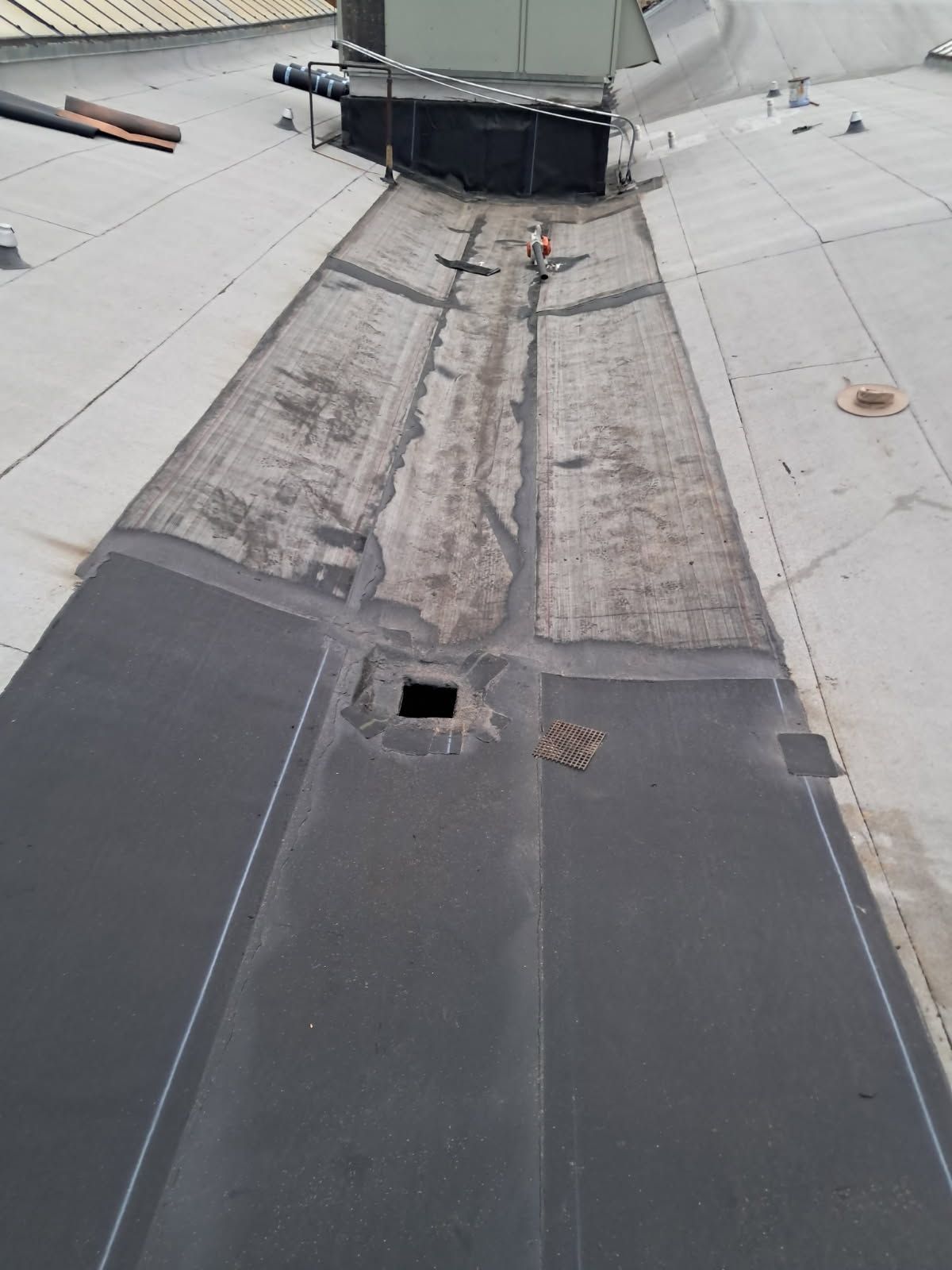 A roof with a hole in it and a drain on it.