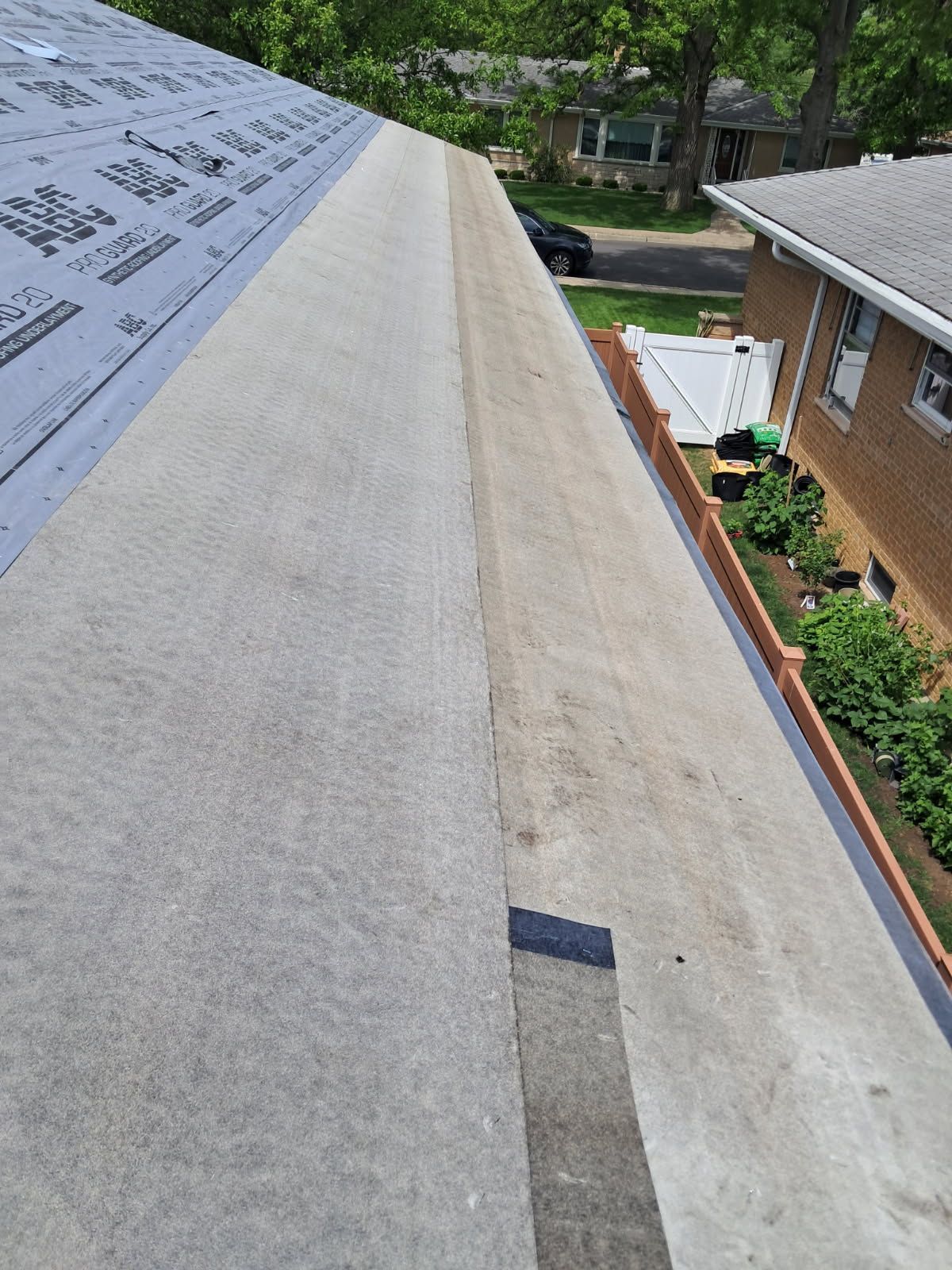 A roof with a lot of shingles on it and a house in the background.