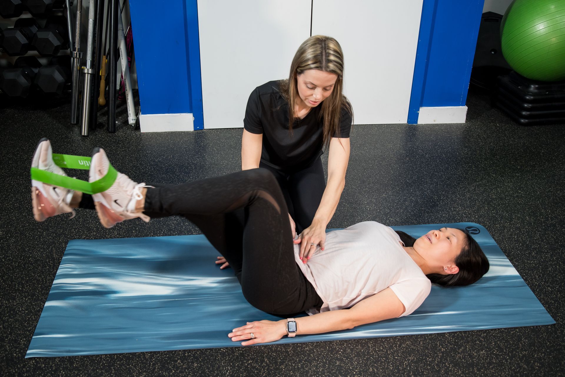 physiotherapist helping pregnant woman exercise on a medicine ball