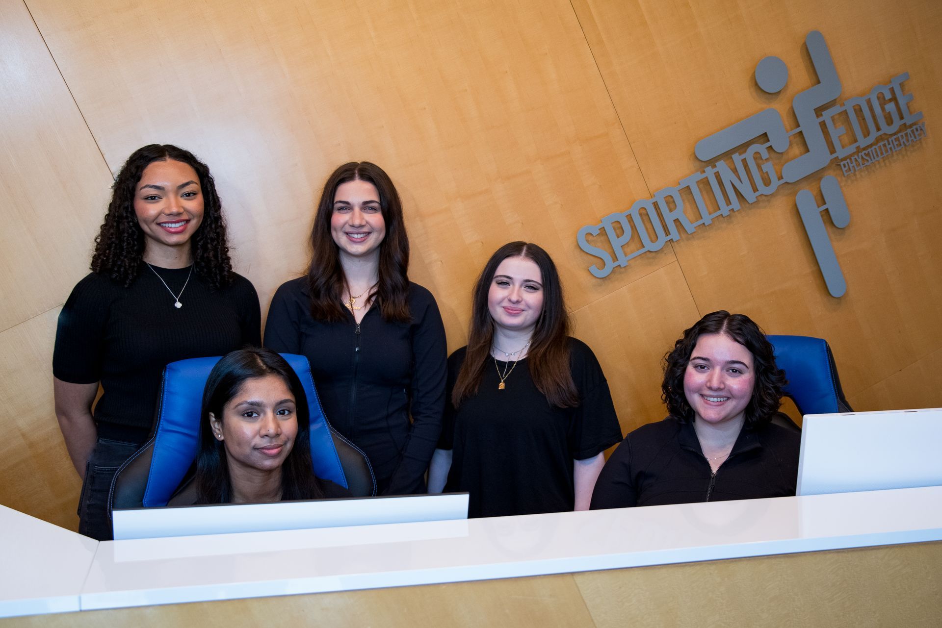 A group of people are posing for a picture in front of a sign that says physiotherapy.