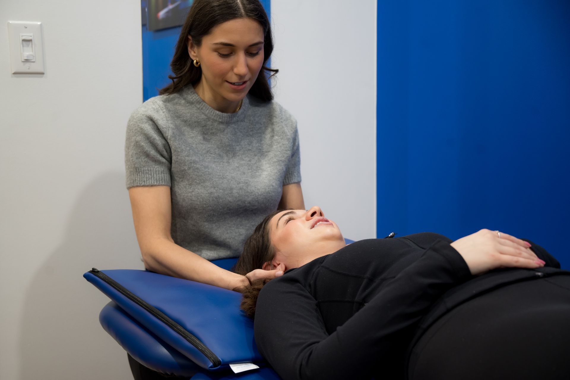 A woman is giving a massage to a woman laying on a table.