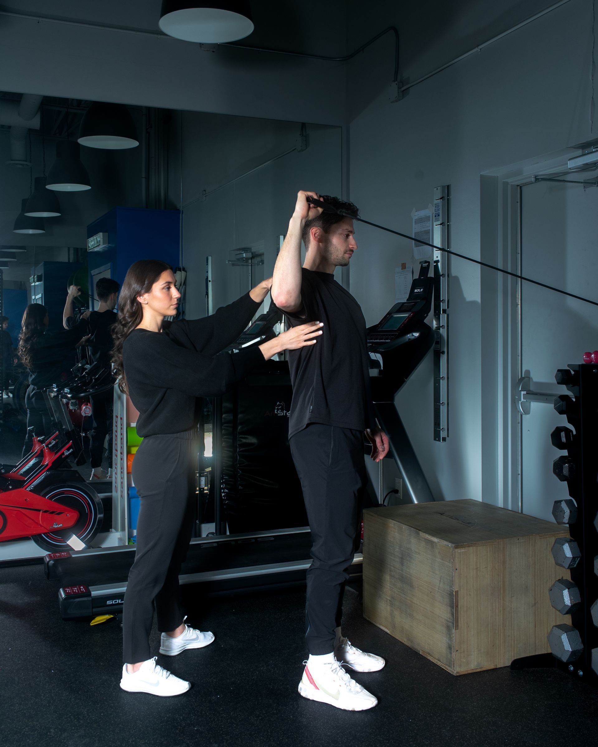 a woman is helping a man stretch his arm in a gym