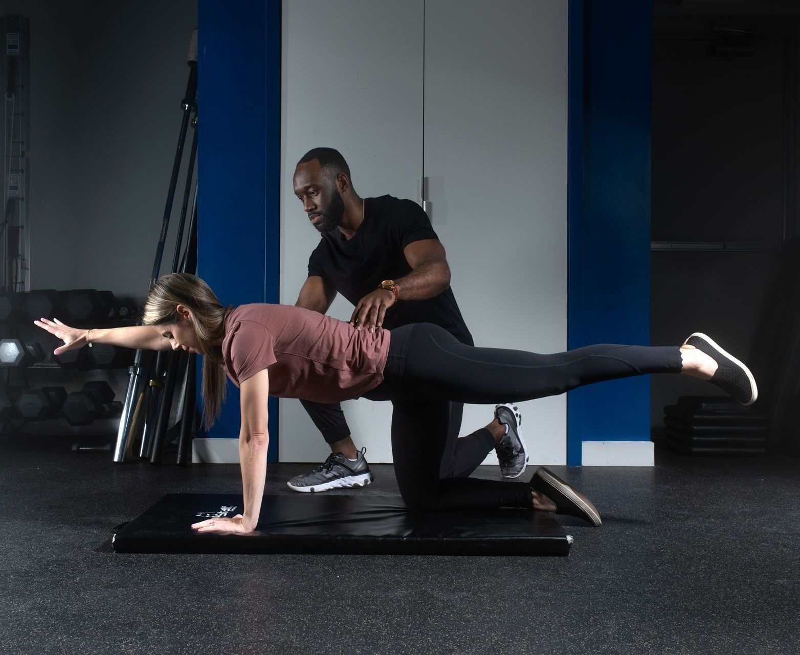a man helps a woman do a plank on a mat