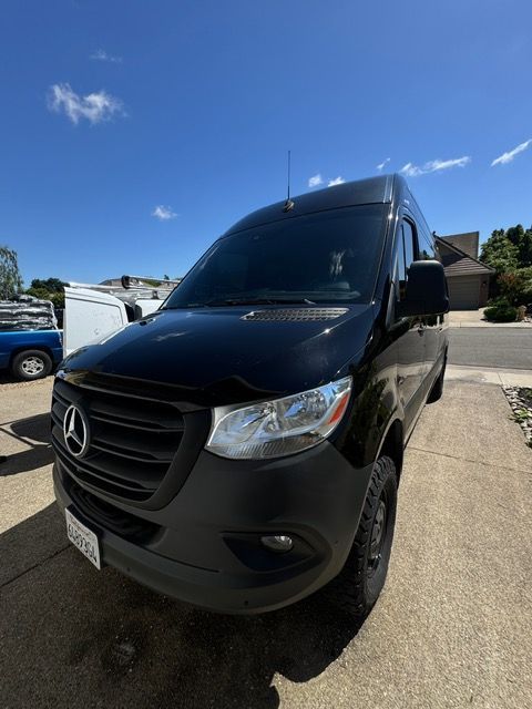 Black Mercedes van parked in a sunny driveway, front view