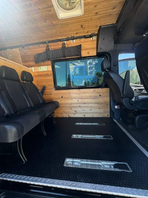 Van interior with wood-paneled walls, black benches, and a window showing a city street