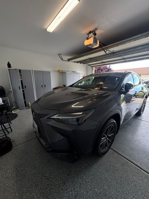 Black SUV parked in a garage with the door open and a ceiling-mounted opener visible