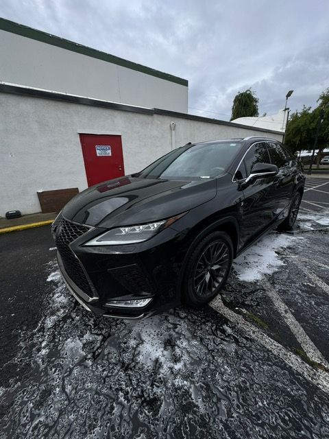 Black SUV parked on a wet lot beside a white building with a red door, with slushy snow on the ground