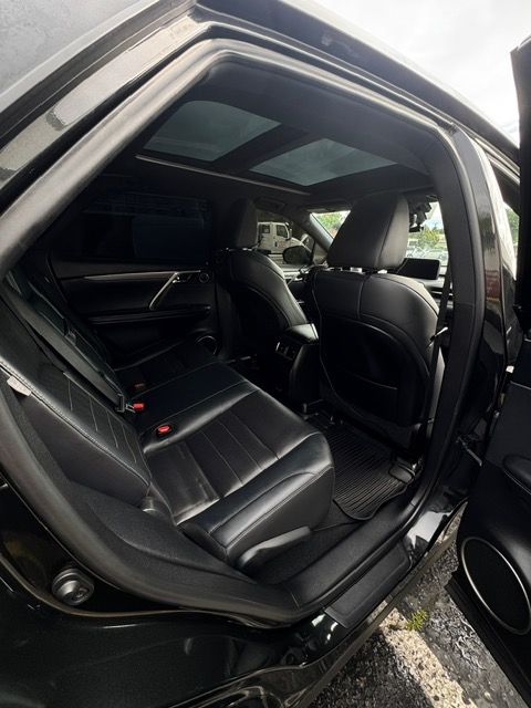 Open car rear door showing black leather back seat and panoramic sunroof