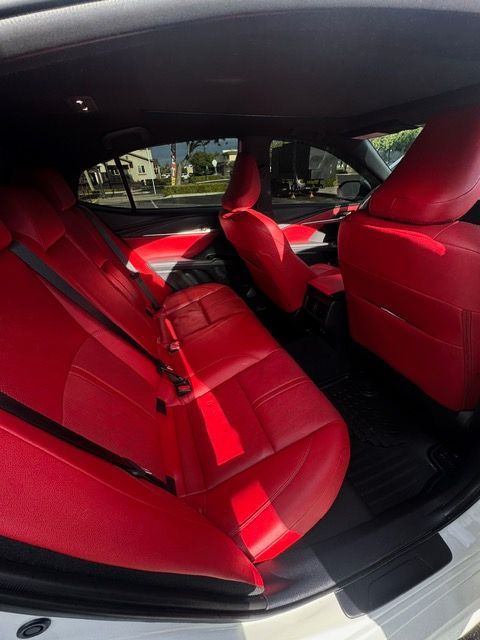 Red car interior with bright red seats and black flooring, viewed from the back seat area