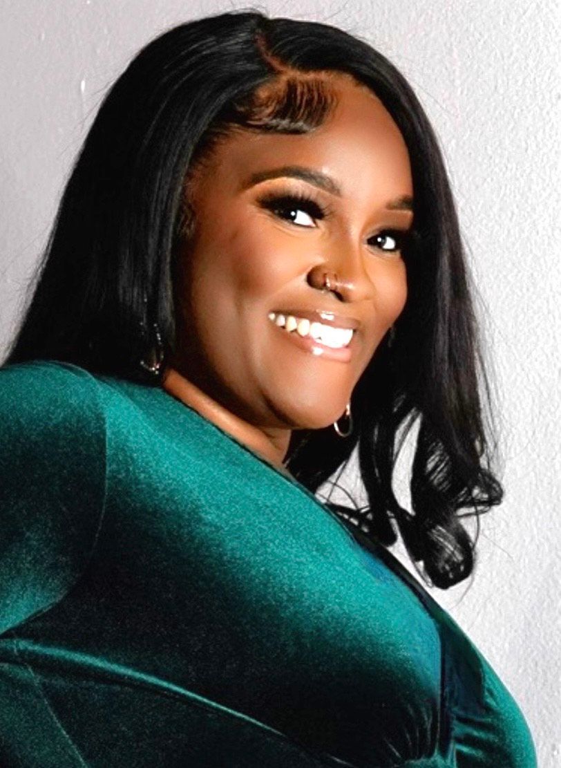 A woman in a green dress is smiling for the camera.