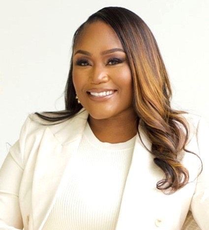 A woman is wearing a white jacket and smiling for the camera.