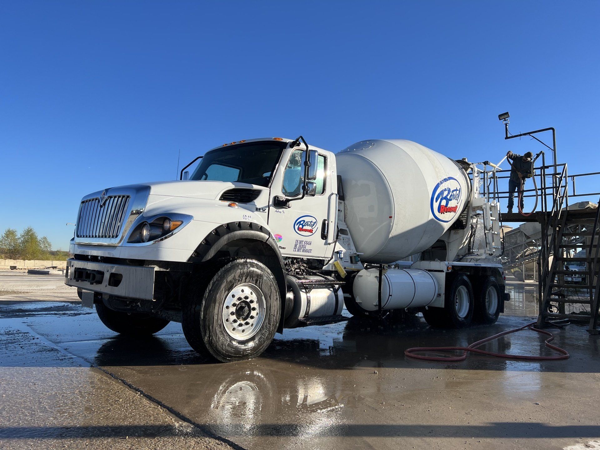 A white concrete mixer truck is parked in a parking lot.