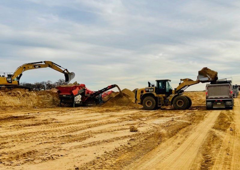 A bulldozer is loading dirt into a dump truck on a dirt road.