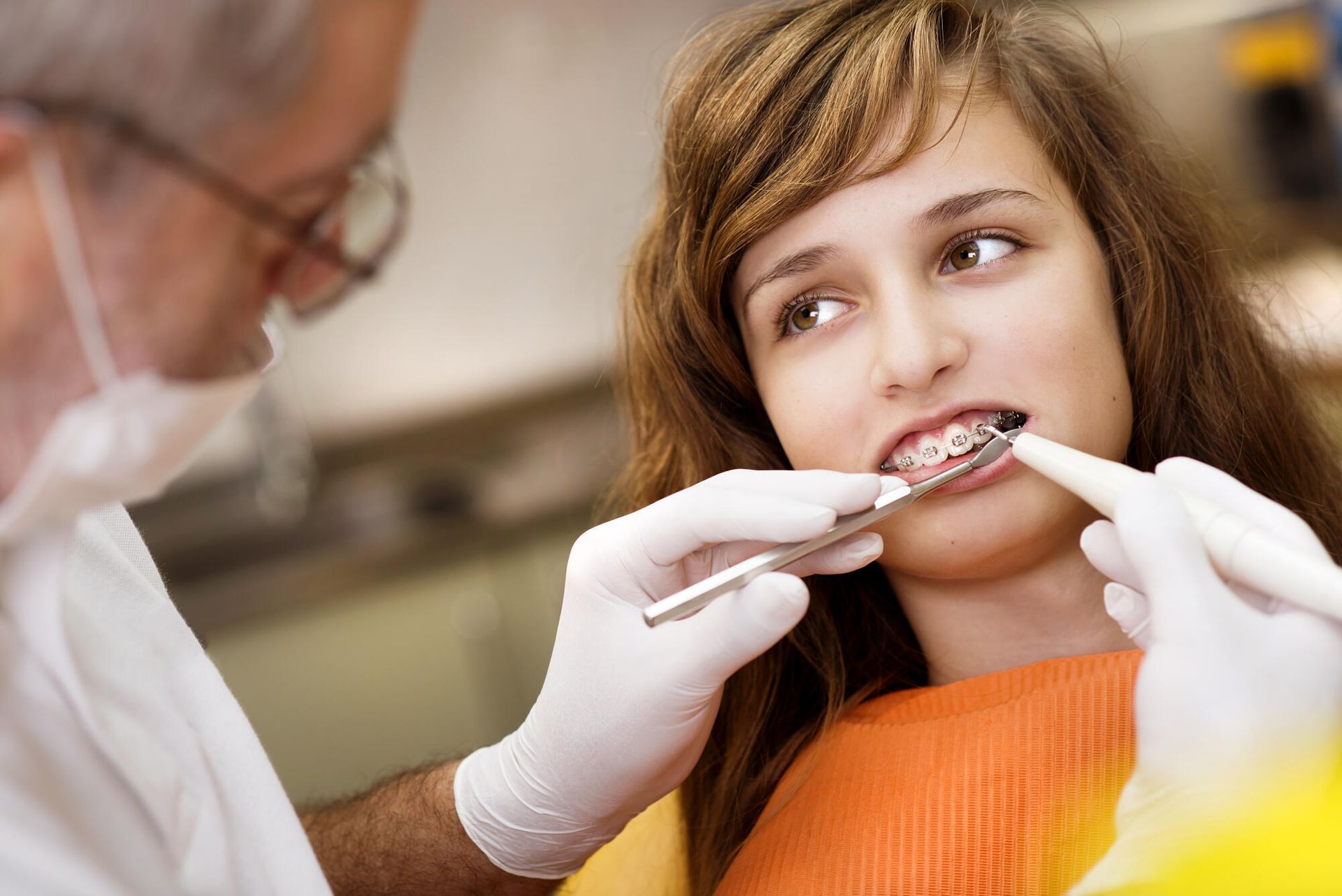 A woman is getting her teeth examined by a dentist.