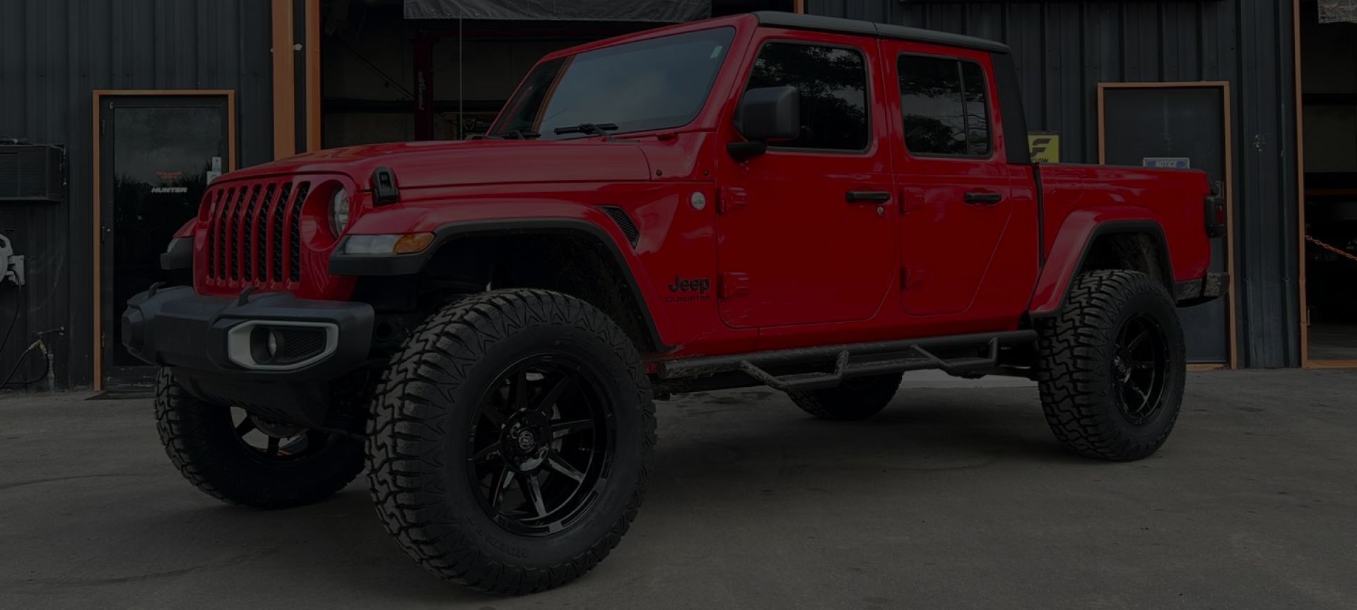 a red jeep is parked in front of a shop | Outlawed Customs