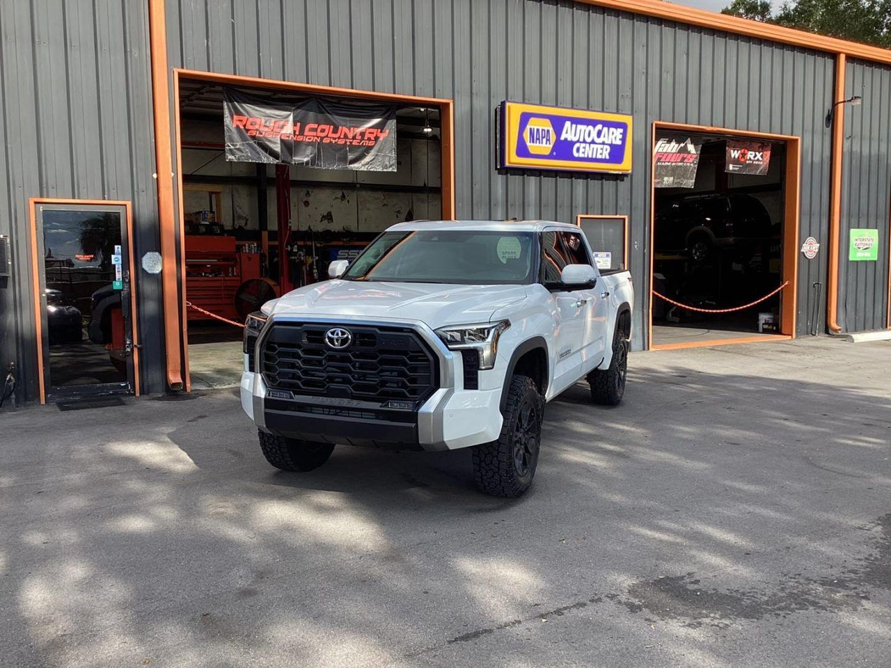 a white truck is parked in front of a shop | Outlawed Customs