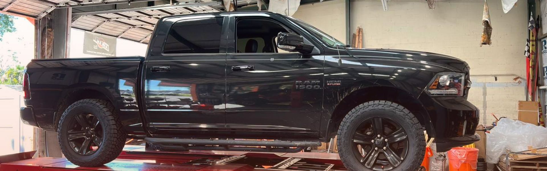 a black truck is sitting on a red hunter lift | Outlawed Customs