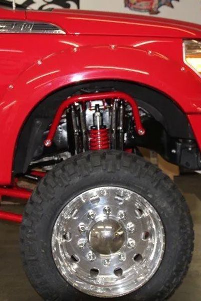 a red truck with chrome wheels and tires is parked in a garage | Outlawed Customs