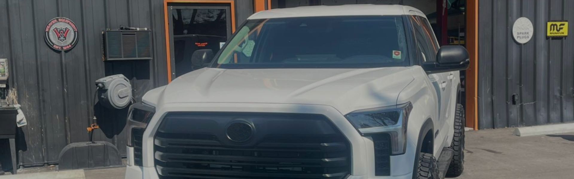 a white Toyota truck is parked in front of a building | Outlawed Customs
