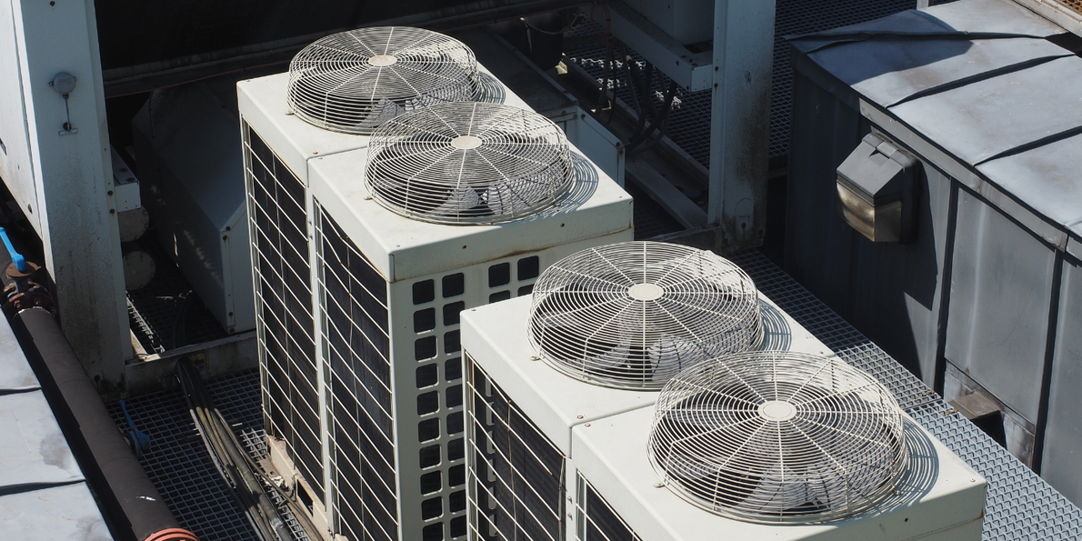 A group of air conditioners are sitting on top of a building.