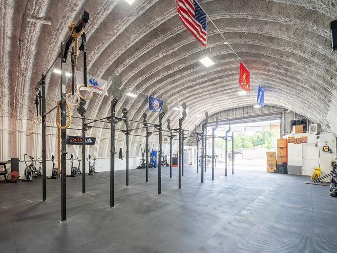 A large empty gym with american flags hanging from the ceiling.