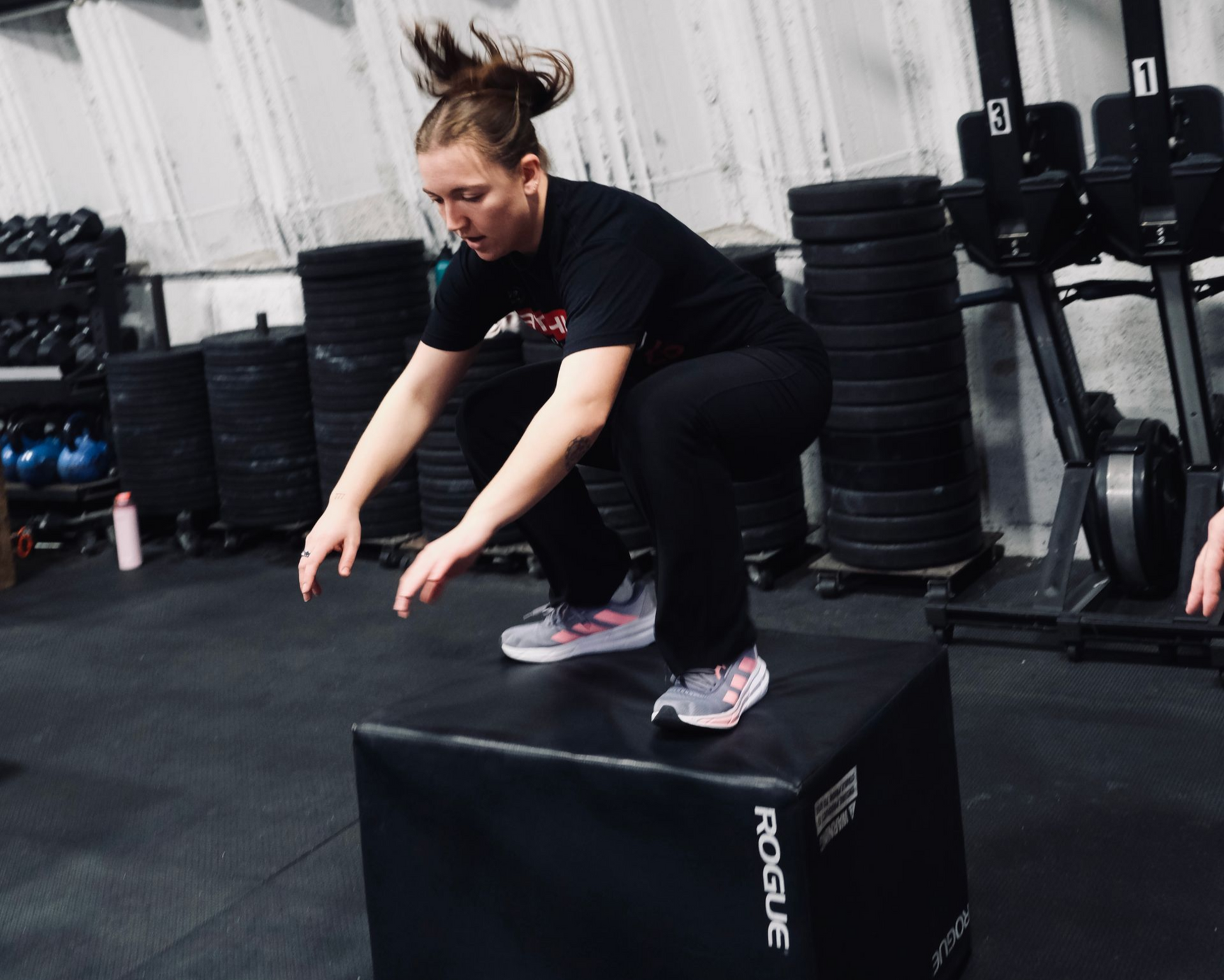 A man is squatting in front of a sign that says crossfit hoboken