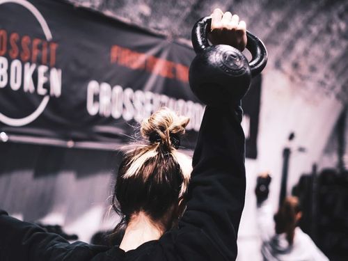 A man is squatting in front of a sign that says crossfit hoboken