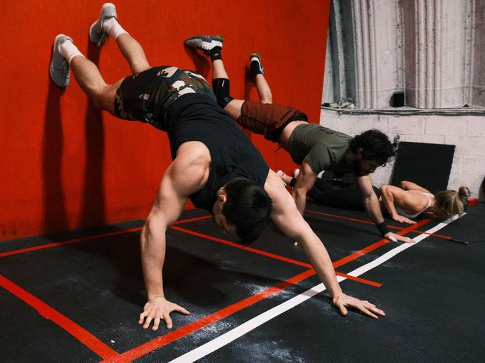 A group of people are doing push ups on a gym floor.